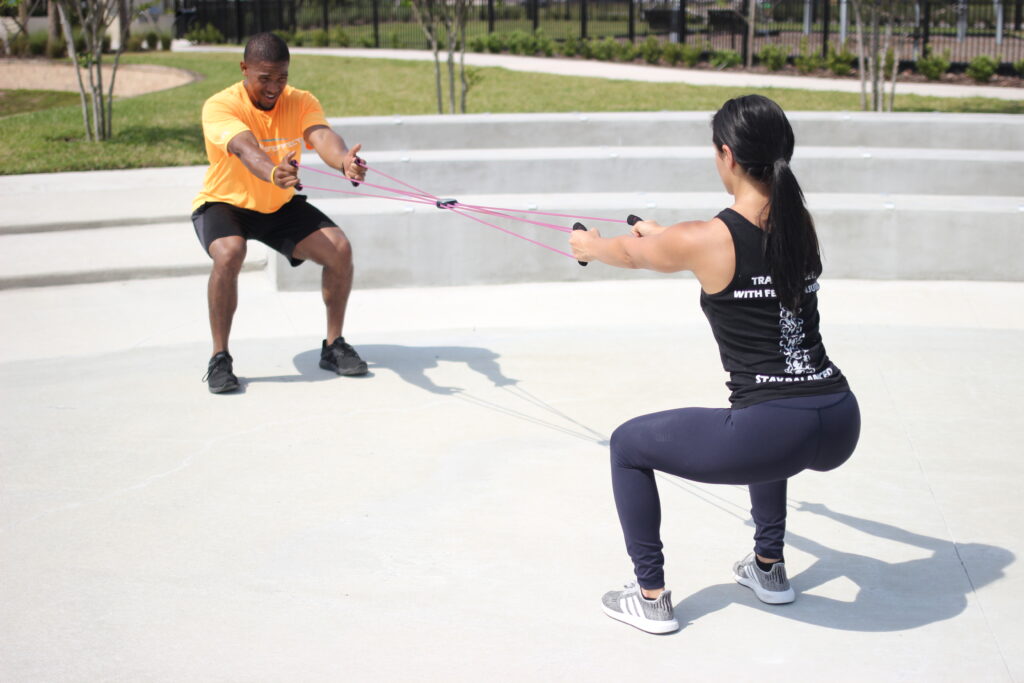 At-home personal training in Apollo Beach, FL. An at-home personal trainer is guiding a client through an outdoor exercise. 